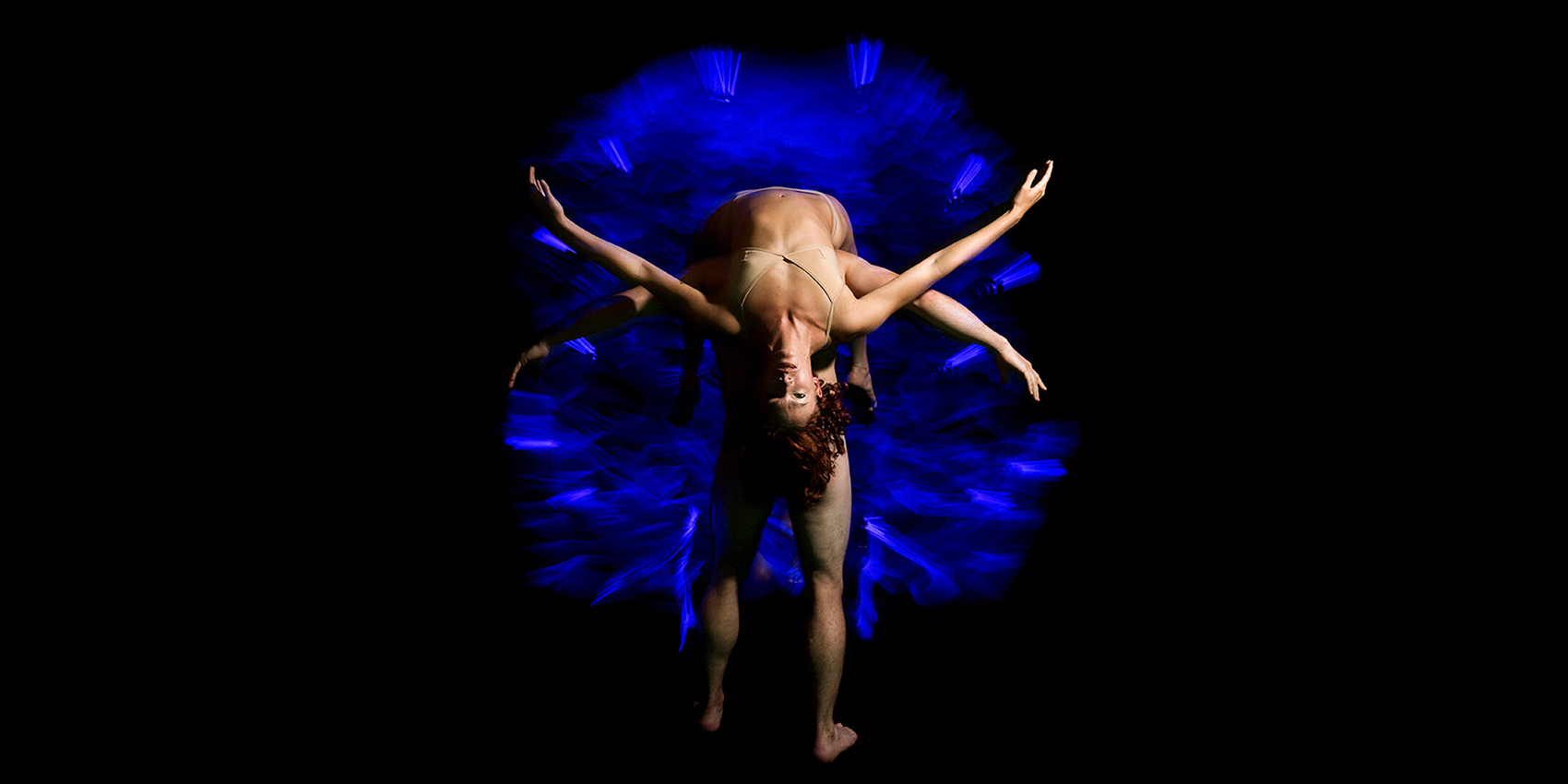Two performers intertwined against a dark background