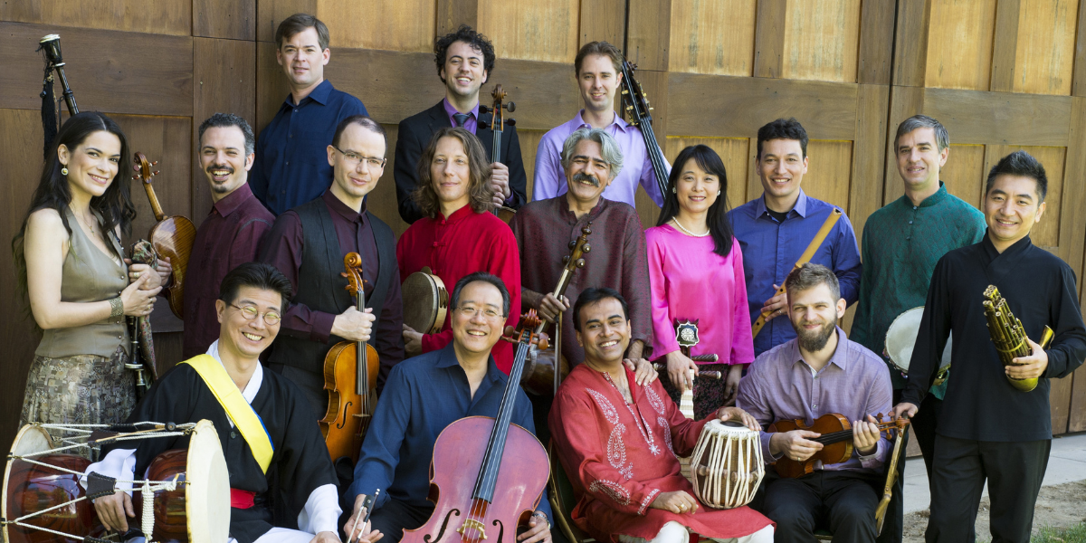 A group of musicians standing a sitting, some holding instruments.
