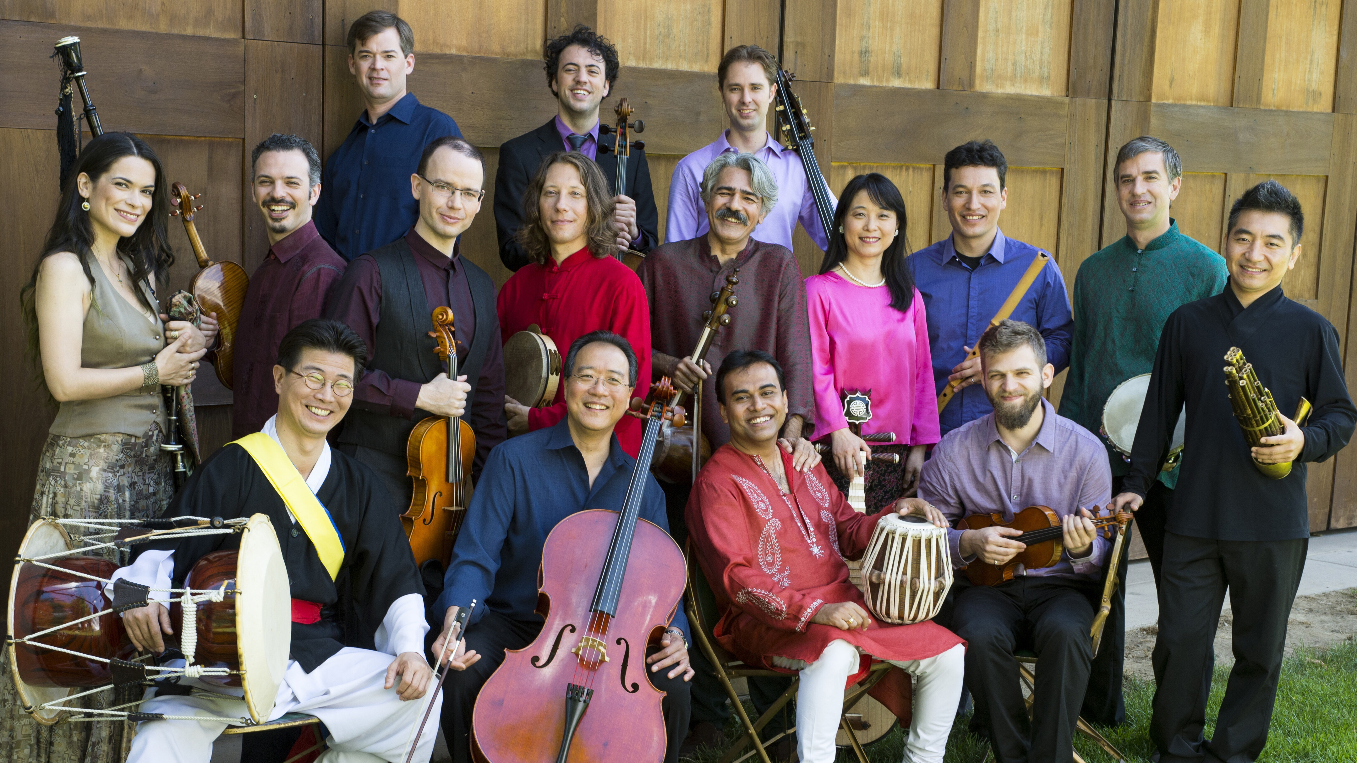 A group of musicians standing a sitting, some holding instruments.