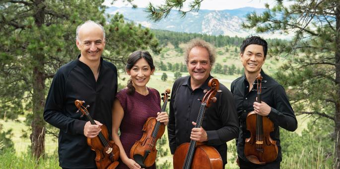Four musicians pose with their string instruments in front of a nature scene