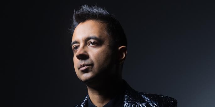 Headshot of person with black hair and black leather suit