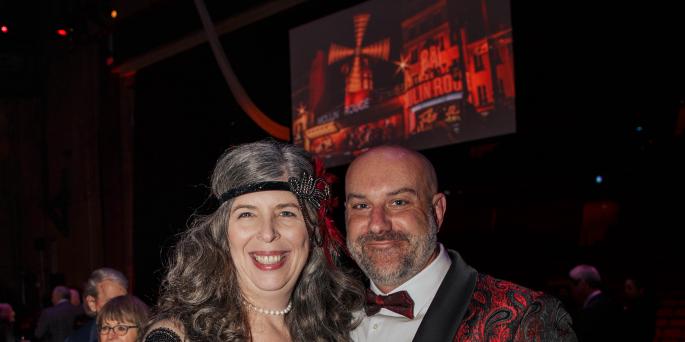 Two people in Moulin Rouge attire smile 
