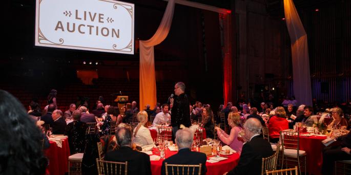 Diners sit on stage with "Live Auction" projected on screen above
