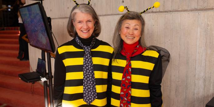 Two people dressed as bees smile
