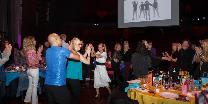 Event attendees dance on dark stage