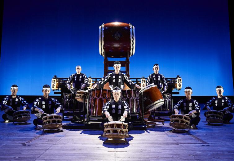 Eight performers on stage surrounded by traditional Japanese drums