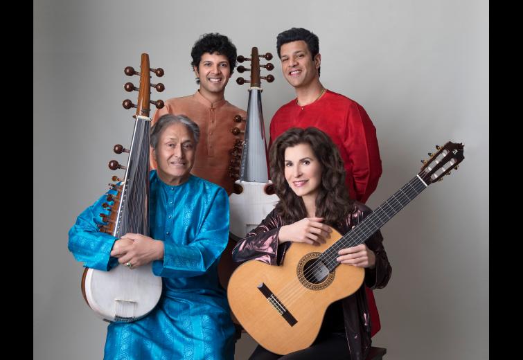 Four musicians pose with instruments in front of a neutral background