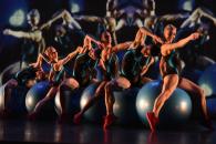 Six MOMIX performers on exercise balls against a dark background