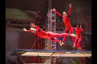 Three Streb performers in aerial poses performing on a trampoline
